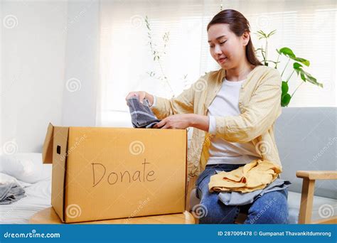 Volunteer Asian Woman Putting Unused Clothes Into Cardboard Boxes For