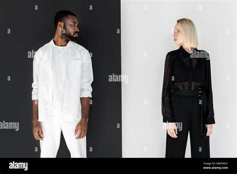African American Boyfriend And Blonde Girlfriend Looking At Each Other Near Black And White Wall