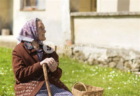 Very Old Woman With Head Scarf Sitting And Relaxing In The Garden