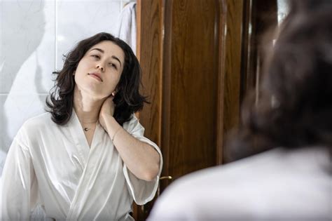 Retrato de una joven latina con un gesto de dolor mirándose a sí misma en el espejo con las