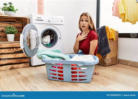 Young Caucasian Woman Putting Dirty Laundry Into Washing Machine Scared