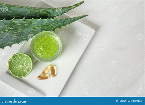 Jar With Aloe Vera Gel Pills And Cut Lime On White Wooden Table Stock