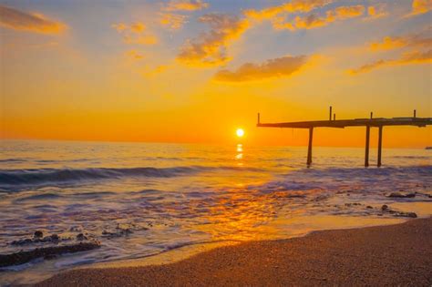 Premium Photo | A sunset over the ocean with a pier in the background