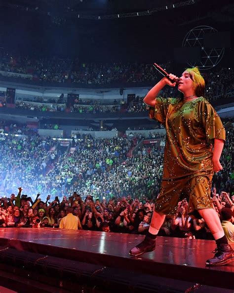 a male in a gold outfit is on stage with his microphone up to the crowd