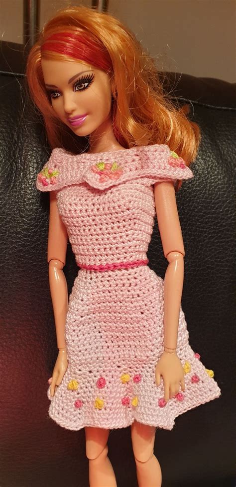 A Doll With Red Hair Wearing A Pink Crocheted Dress And Shoes Standing