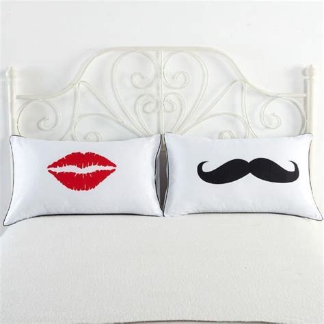 A White Bed Topped With Two Pillows Covered In Red Lipstick And A Moustache