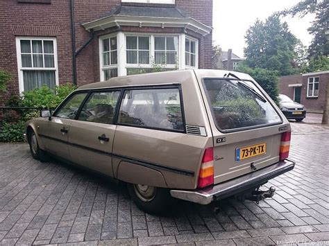 An Old Car Parked In Front Of A Large Brick Building On A Cobblestone