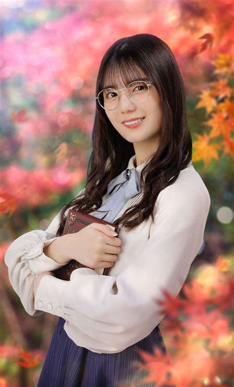 A Woman With Glasses Is Posing In Front Of Colorful Leaves And Trees