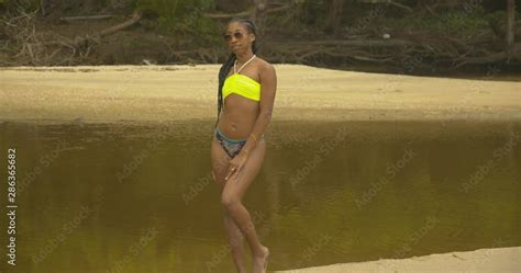 Slim sexy model posing in a bikini with a shallow river flowing in the background Stock ビデオ