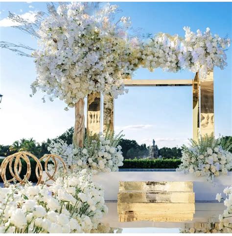 An Outdoor Wedding Setup With White Flowers And Greenery On The Ground