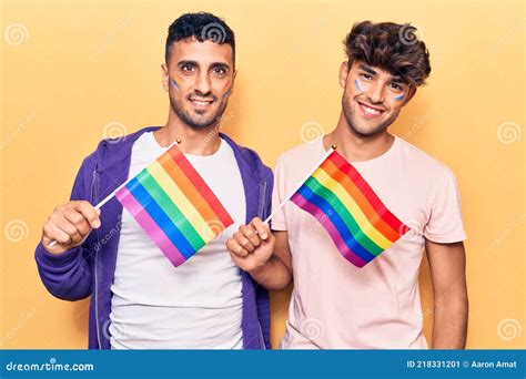 Joven Pareja Gay Sosteniendo Banderas Lgbtq Arcoiris Con Aspecto Positivo Y Feliz De Pie Y
