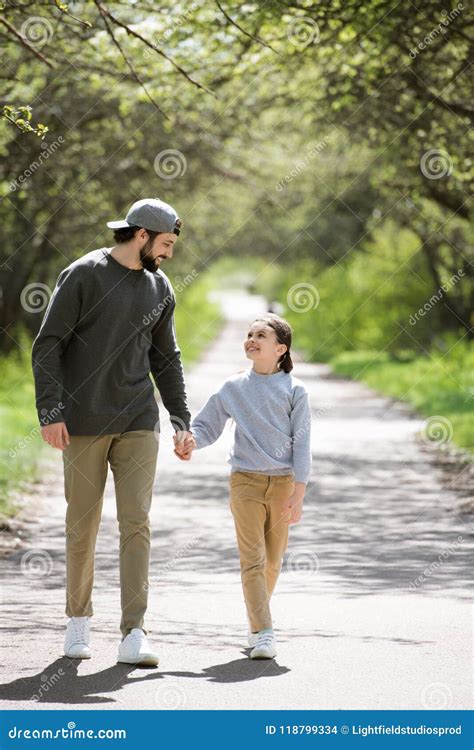 Padre E Hija Sonrientes Que Caminan Y Que Llevan A Cabo Las Manos Foto