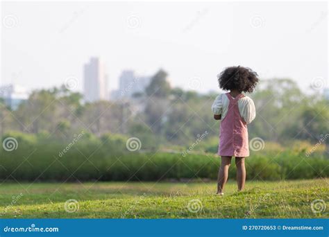 A Dark Haired Curly Haired Girl In A Pink Dress Stood Staring Out At