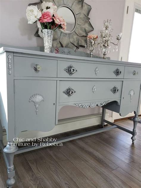 An Old Dresser Is Painted Gray And Has Flowers On Top