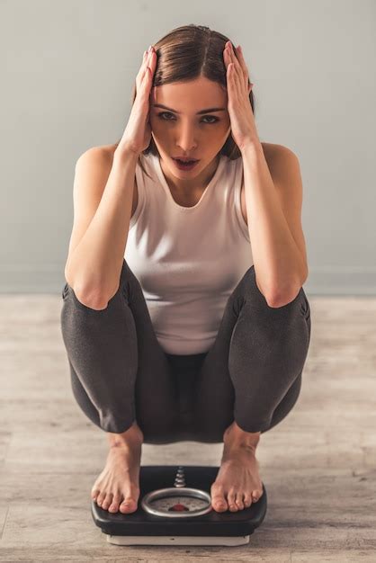 La muchacha está sosteniendo su cabeza mientras se pone en cuclillas en