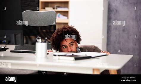 Scared Man Hiding Behind Office Desk In Room Stock Photo Alamy