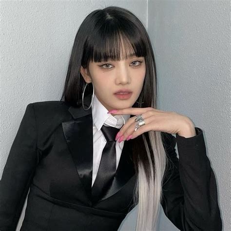 A Woman With Long Black Hair Wearing A Suit And Tie Posing For The Camera