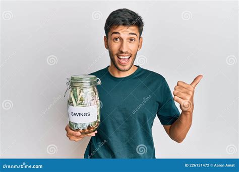 Joven Y Guapo Hombre Sosteniendo Un Frasco Con Ahorros Apuntando El