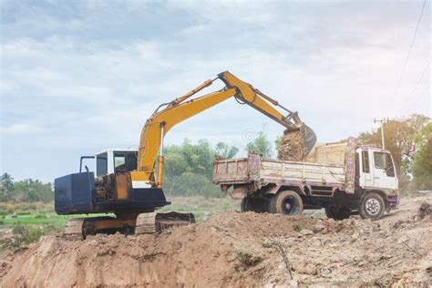 Yellow Excavator Machine Loading Soil Into A Dump Truck At Construction