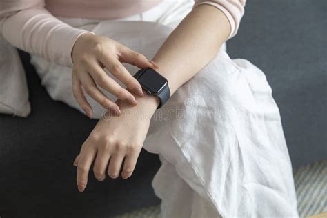 Close Up Of Woman Checking Smart Watch Sitting On Sofa Stock Photo