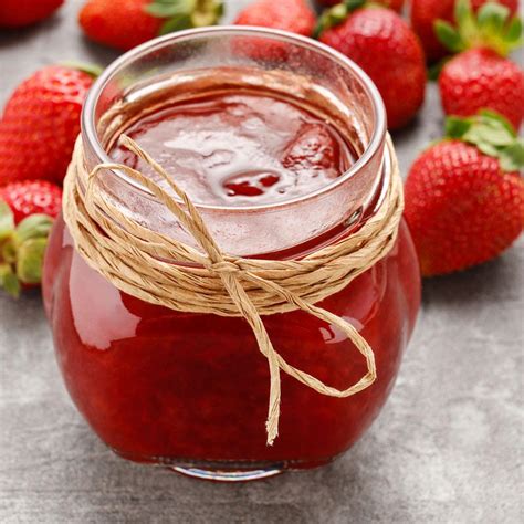 A Jar Filled With Liquid Surrounded By Strawberries