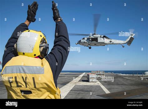 Aviation Boatswain S Mate Directs An MH 60S Sea Hawk Helicopter Stock