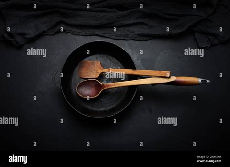 Empty Round Cast Iron Frying Pan With Wooden Handle On Black Table Top