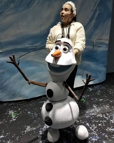 a woman standing next to a statue of a snowman in front of a backdrop