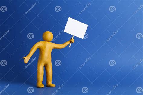 Human Figure Made Of Yellow Plasticine Holding Blank Sign On Blue