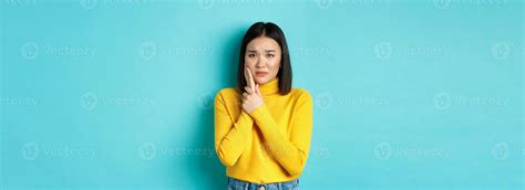 Victim of domestic violance, young asian woman, touching cheek and