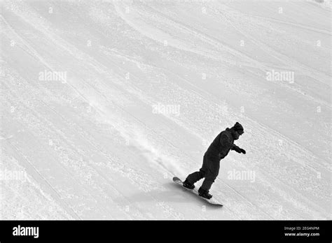 Snowboarder Downhill On Snow Grooming Ski Slope At Cold Winter Day