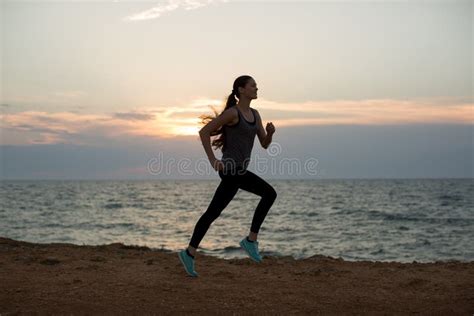 Silhouette of a Young Girl Running Along the Beach of the Sea during an ...