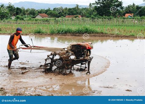 Indonesia Farmer Plowing A Rice Field Using Tiller Tractor Editorial