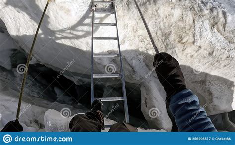 A Climber Crosses A Large Deep Crack In The Glacier By A Metellic