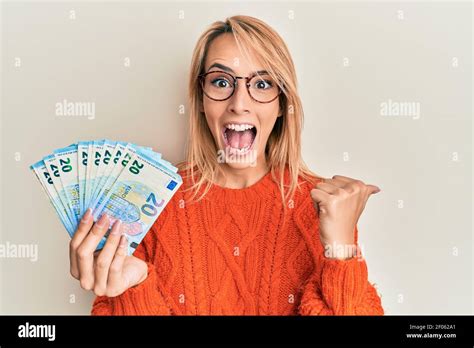 Belle Femme Blonde Portant Billets En Euros Pointant Du Pouce Vers Le Haut Sur Le C T