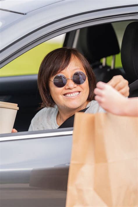 Smiling Mature Asian Woman In A Car Exchanging A Paper Bag Stock Image Image Of Relaxation