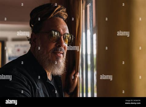 Side View Of Bearded Mature Male In Casual Outfit With Sunglasses And Dreadlocks Standing Near