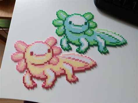 Two Cross Stitch Stickers Sitting On Top Of A White Table Next To A