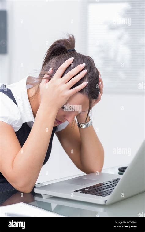 Frustrated Business Woman Sitting With Head In Hands In Front Of Laptop