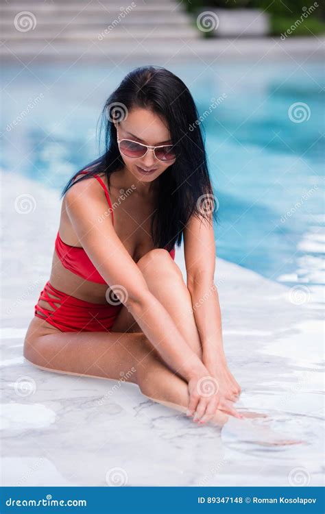 Elegant Woman In The Red Bikini On The Sun Tanned Slim And Shapely Body Is Posing Near The