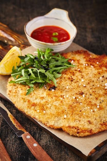 Premium Photo Pork Schnitzel With Tomato Sauce On Dark Wooden Background