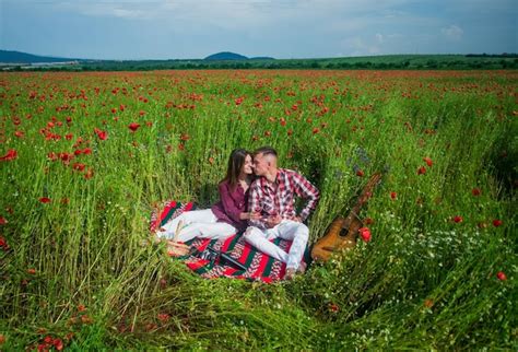 Joven pareja feliz abrazándose y besándose en el campo de amapolas amor