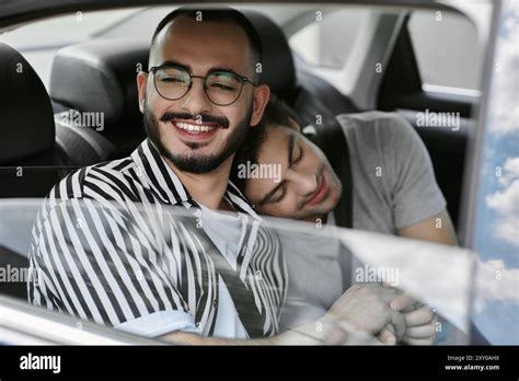 Happy Gay Couple In Car One Looking Out Window Other Resting Head On Partner S Shoulder Stock