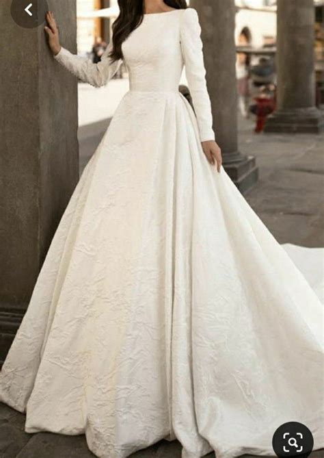 A Woman In A White Wedding Dress Standing Next To Pillars With Columns