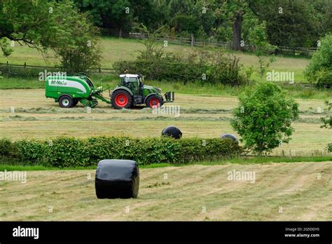 Hay Or Silage Making Farmer In Farm Tractor At Work In Rural Field