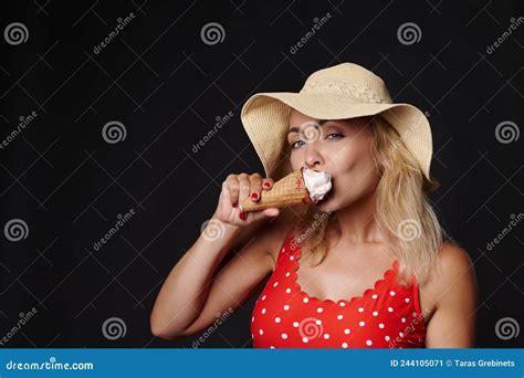 Belle Femme Blonde Européenne En Chapeau D été Et Maillot De Bain Rouge En Mangeant Une