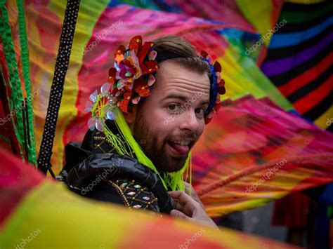 Un joven caucásico en el orgullo gay de París luciendo barba sacando la lengua mirando a