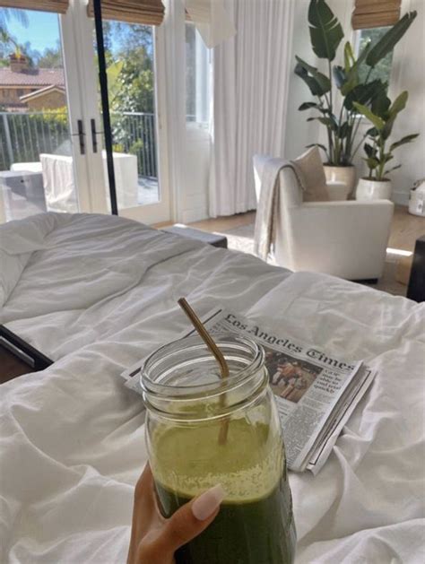 A Person Is Holding A Drink In Front Of A Bed With A Magazine On It