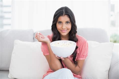 Premium Photo Content Cute Brunette Sitting On Couch Holding Popcorn Bowl