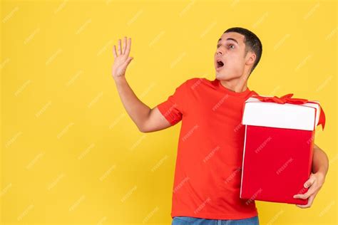 Free Photo Front View Of Young Man Holding Present On Yellow Wall